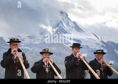 Vier traditionell gekleideten Einheimischen spielt Alphorn gegen Matterhorn, Zermatt, Wallis, Schweiz Stockfoto