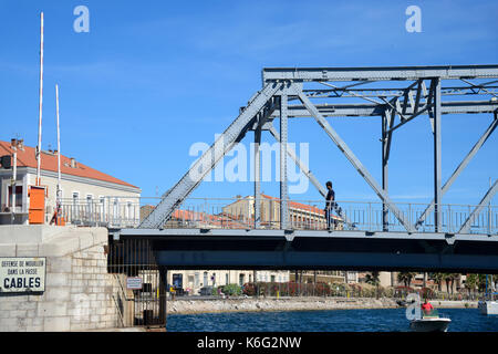 Mann, der über eine Box-Träger-Eiserne Brücke über den Royal Canal bei Sète oder Sete Herault Languedoc-Roussillon Frankreich geht Stockfoto