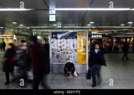 YOKOHAMA, Japan - Dezember 2016 - Nicht identifizierte Person sitzt in der Mitte der Yokohama Station, während die Durch sind Stockfoto