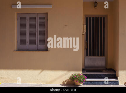 Altes Haus Eingang und Fenster, dekorative violette Blumen in Vase vor. Stockfoto