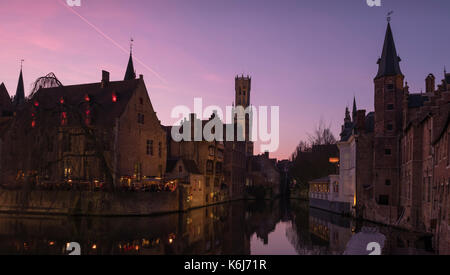 Romantischer Sonnenuntergang an einem schönen Kanal in der Altstadt von Brügge in Belgien mit dem Belfried mittelalterlicher Glockenturm im Hintergrund. Stockfoto