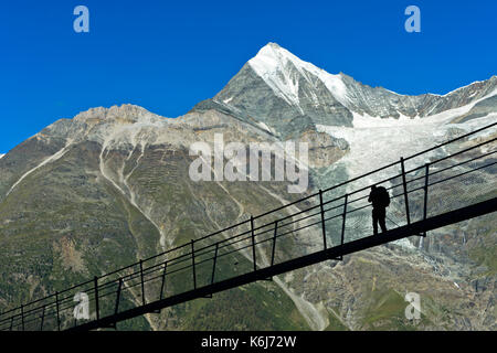 Wanderer gegen das Weisshorn Spitze in der Hintergrundbeleuchtung auf dem Charles Kuonen Suspension Bridge, die längste Fußgänger-Hängebrücke der Welt, Randa, Wallis Stockfoto