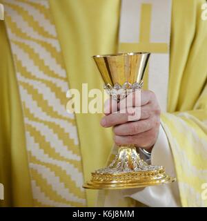 Der katholische Priester hält einen Kelch Stockfoto