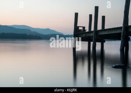 Ein Pier gegen den Sonnenuntergang im Derwent Water im englischen Lake District. Stockfoto