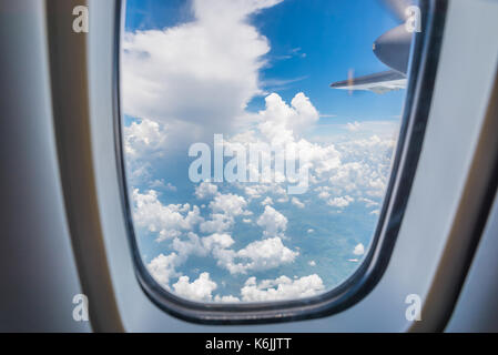 Wolken und Himmel, wie man sie durch ein Fenster eines Flugzeugs sieht. Stockfoto