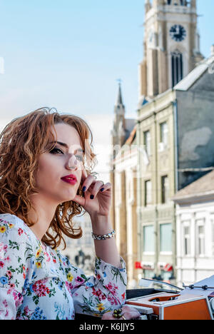 Junge Frau, Retro Look, sitzen an der Schreibmaschine, Portrait. Hinzugefügt Lärm. Eine Frau sitzt auf einer Terrasse oberhalb der Stadt und nachdenklich in den dis suchen Stockfoto