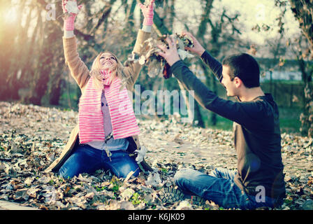 Teenager Jungen und Mädchen spielen in den Blättern und freuen uns auf Herbst und Freundschaft Stockfoto