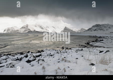 SEwards - Schnee Ytresand Strand - Sandbotnen Bucht - stürmischen Himmel. - Bora-Nesfjellet Volandstinden-Sautinden - Nonstinden-Stortinden - Flakstadtinden montieren Stockfoto