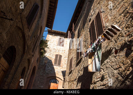 Waschen heraus hängen auf einer Linie zu trocknen, hoch oben aus dem Fenster eines Hauses in San Gimignano, Toskana Italien Europa EU Stockfoto
