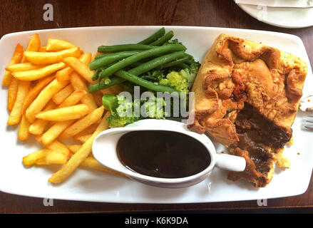 Britische Mittagessen - Steak pie mit Chips, Brokkoli und Sauce Stockfoto