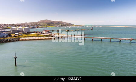 Piers und Kraftstofftanks in Holyhead Hafen im Norden von Wales, mit Stadt und Holyhead Holyhead Berg hinter. Stockfoto