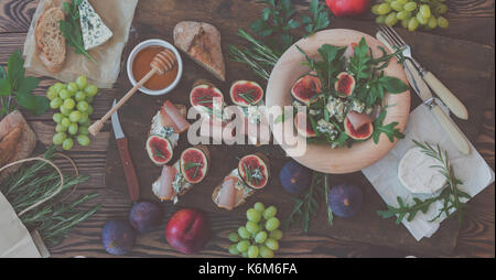 Einfache Diät Salat mit Rucola, Feigen und Blauschimmelkäse auf ein braunes Holz- Oberfläche. Sandwiches mit Ricotta, frische Feigen, Prosciutto, Rosmarin und blauen Käse Stockfoto