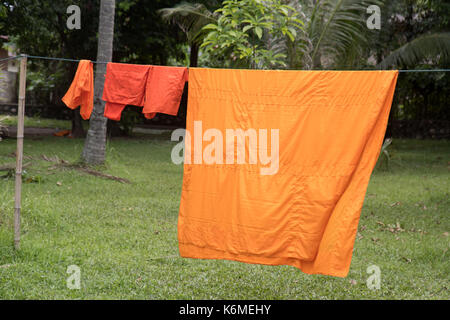 Die orangefarbenen Roben der Mönche sind auf einem Seil in das buddhistische Kloster getrocknet Stockfoto