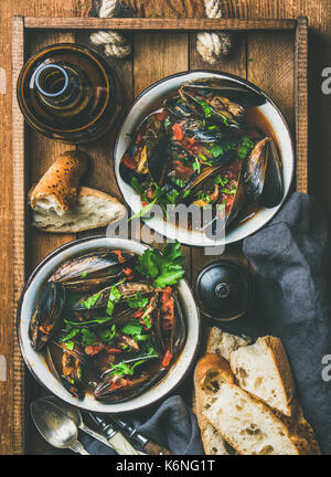 Flachbild-lay von gekochten Muscheln in Tomatensauce und helles Bier Stockfoto