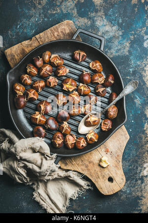 Geröstete Kastanien im grillen Schwenk über dunkelblauen Hintergrund Stockfoto