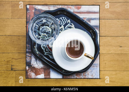 Türkischer Kaffee mit einem Glas Wasser auf Holztisch, Ansicht von oben Stockfoto