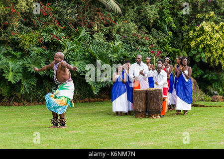 Ruandische männlichen Tänzer der traditionellen ruandischen Intore Tanz mit Drummer im Hintergrund Stockfoto