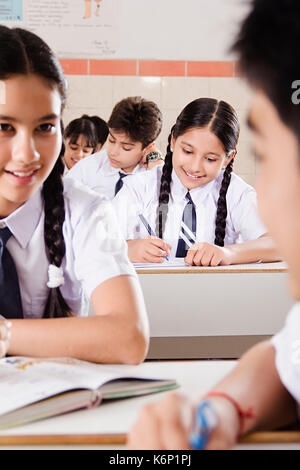 Indische Junge und Mädchen High School jugendliche Studenten sprechen Klatsch im Klassenzimmer sitzen Stockfoto