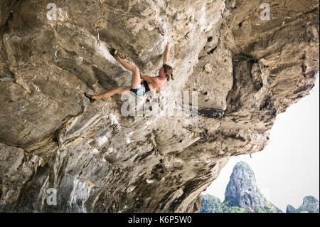 Eine Frau klettern auf einen der überhängenden Klippen in der Nähe von Ton Sai Beach, Railay Halbinsel, Krabi, Thailand. Stockfoto