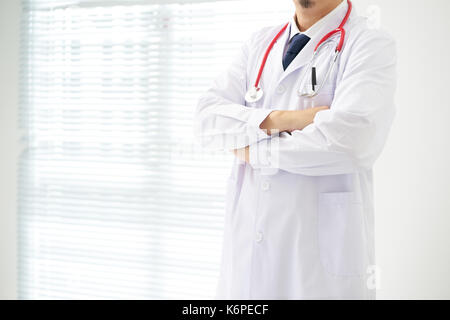 Unknow Arzt mit Waffen im Büro gekreuzt Posieren, er trägt ein Stethoskop. Stockfoto