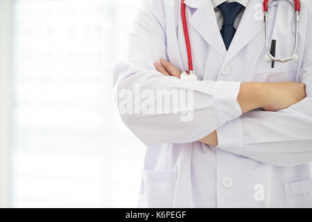 Unknow Arzt mit Waffen im Büro gekreuzt Posieren, er trägt ein Stethoskop. Stockfoto