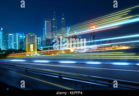 Ansicht von der Seite der Überführung, verschwommene Bewegung Wirkung mit leichten Wanderwegen und schönen Stadt Skyline im Hintergrund. Stockfoto