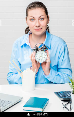 Vertikale Portrait von geschäftsfrau am Tisch mit einem Wecker in den Händen Stockfoto