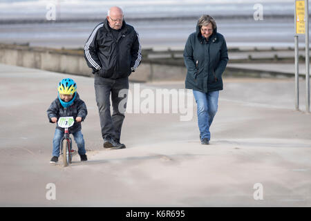 Ältere Paare der Mann und die Frau zu Fuß entlang Sand geblasen Promenade in Rhyl in Nord Wales bei Unwetter Aileen, Denbighshire, Wales, Großbritannien Stockfoto