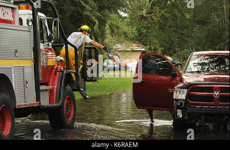 Orlando, USA. 12 Sep, 2017. A A Fire Rescue worker eine Flasche Wasser zu einem Mann treibt ein deaktiviert Pickup Truck durch eine Straße in der Orlo Vista Nachbarschaft von Orlando, Florida, am 12. September 2017, in den frühen Morgenstunden des 11. September als Hurrikan Irma überschwemmt wurde durch den Bereich übergeben. Die Nationalgarde und Orange County Fire Rescue Personal gerettet 151 Bewohner von Häusern, die hatten so viel wie 4 Fuß Wasser in ihnen. 550 Häuser wurden beschädigt. Credit: Paul Hennessy/Alamy leben Nachrichten Stockfoto