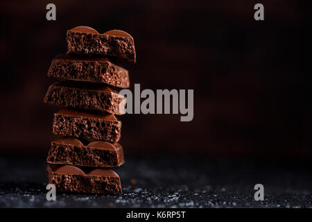 Poröse Schokolade in auf einem schwarzen Hintergrund closeup Stack. Stücke von Milch poröse Schokolade, übereinander liegen. Unter ihrem Text platzieren. Stockfoto