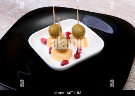 Käse Häppchen mit Oliven und Getreide des Granatapfels auf Holz Fach hautnah. Stockfoto