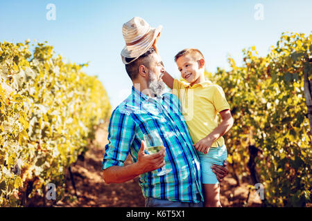 Schönen Lächeln auf den Vater und seinen niedlichen Sohn Spaß an einem Weinberg. Stockfoto