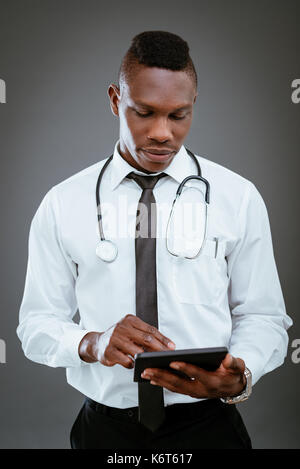 Afrikanische Arzt mit Stethoskop stehend und mit digitalen Tablet. Stockfoto
