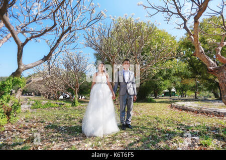 Foto von Vor Hochzeit Asiatische Paare unter einem Baum in einem Blumengarten im Konzept der Beginn einer Partnerschaft leben und Familie. Stockfoto