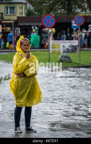 Sarbinowo, Polen - August 2017: Mädchen Kleider im gelben Regenmantel um Hilfe ruft auf Ihrem Mobiltelefon nach extrem starke Regenfälle Stockfoto