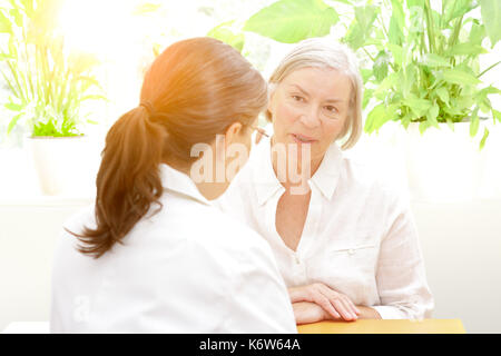 Ältere Patienten etwas diskutieren im Vertrauen mit Ihrer Ärztin für Geriatrie an einem sonnigen Nachmittag, freundliche Atmosphäre Stockfoto