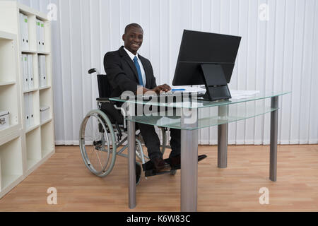 Portrait von Happy afrikanischen Geschäftsmann arbeiten im Büro zu Sitzen im Rollstuhl Stockfoto