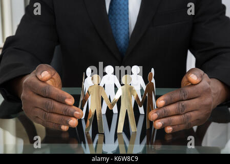 Nahaufnahme der Geschäftsmann Hände schützen Papier Ausschnitt Menschen am Schreibtisch Stockfoto