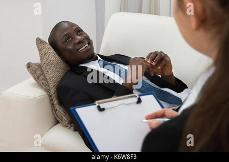 Weibliche Psychiater Notizen In der Vorderseite des Patienten während der psychologischen Therapie Sitzung Stockfoto
