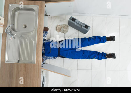 Hohe Betrachtungswinkel der Heimwerker liegend auf dem Boden Reparatur Spülbecken in der Küche Stockfoto