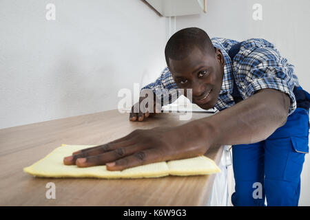 Foto von jungen afrikanischen Mann Reinigung Küchenarbeitsplatte Stockfoto