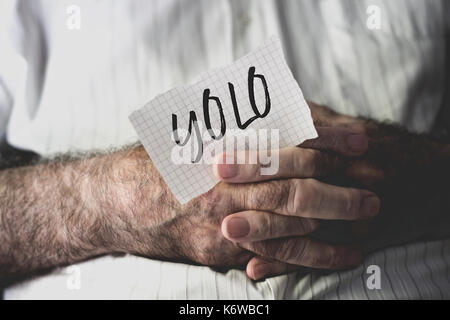 Nahaufnahme eines alten weißen Mann mit einem Hinweis in seine Hände mit dem Wort Yolo, denn sie leben nur einmal, in der es geschrieben Stockfoto