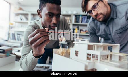 Zwei männliche Architekten im Büro diskutieren Bauvorhaben. Die jungen Männer arbeiten gemeinsam an neuen Gebäude Modell. Stockfoto