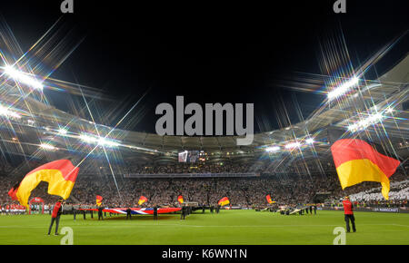 Flaggenschwenker mit deutschen Fahnen vor dem Spielbeginn, Fußballstadion mit Flutlicht am Abend Stockfoto