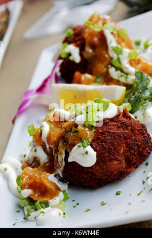 Zwei Gourmet Crab Cakes gekrönt mit saurer Sahne und Schnittlauch auf eine phantastische Sea Food Restaurant. Stockfoto