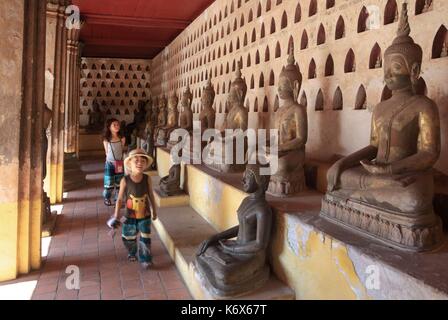 Laos, Vientiane, Kinder vor der alten Statuen von Buddha in der Galerie der alten Tempel von Vat Phra KŽo umgewandelt in eine religiöse Museum Stockfoto