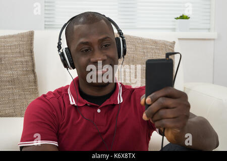 Nahaufnahme der jungen afrikanischen Mann Musik hören über Kopfhörer Stockfoto