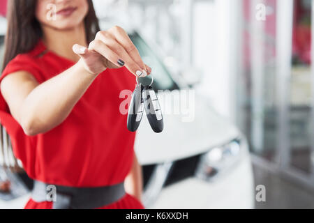 Lächelnd Autoverkäufer Übergabe ihres neuen Autoschlüssel, Ho und Vertriebskonzept. Happy girl der Käufer. Stockfoto
