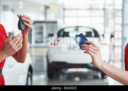 Lächelnd Autoverkäufer Übergabe ihres neuen Autoschlüssel, Ho und Vertriebskonzept. Happy girl der Käufer. Stockfoto