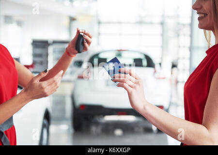 Lächelnd Autoverkäufer Übergabe ihres neuen Autoschlüssel, Ho und Vertriebskonzept. Happy girl der Käufer. Stockfoto